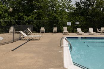 A pool with a fence and chairs around it.
